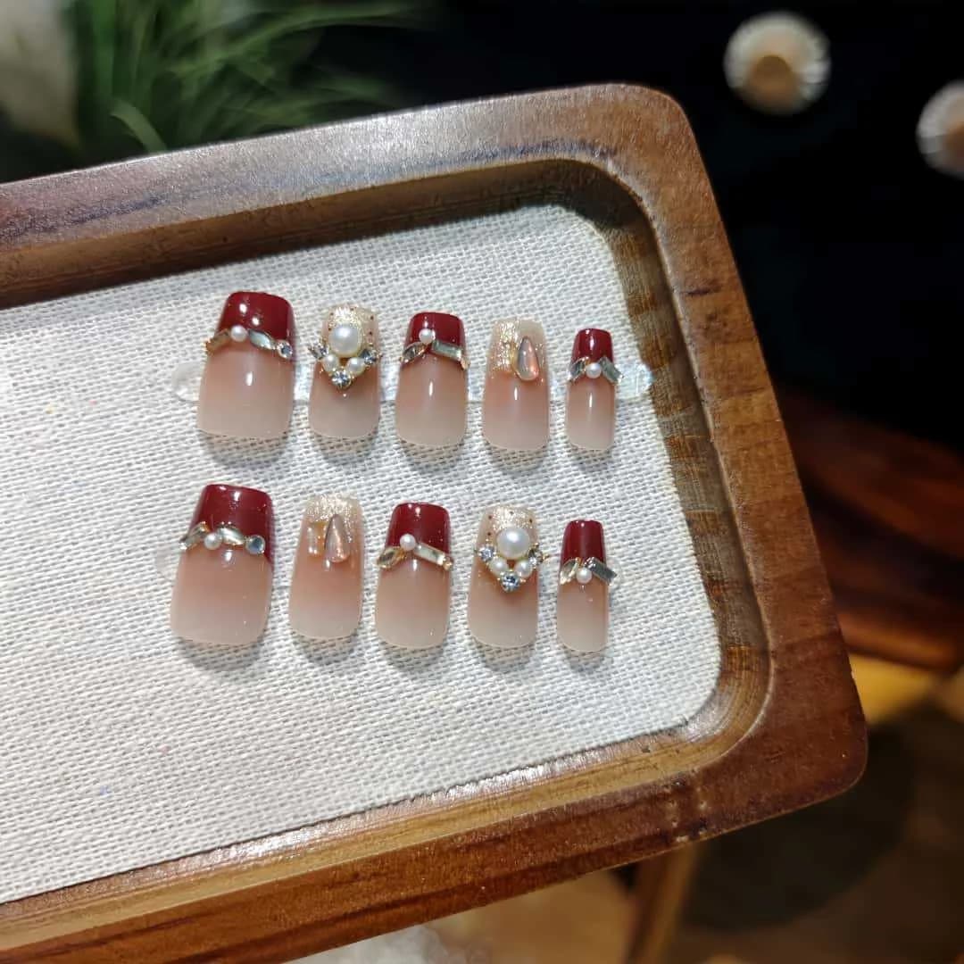 Crvene umjetne nokte s bisernim efektom, kratki lijes, francuski vrh s glitterom